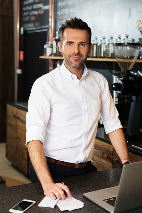 Man in his cafe working on a laptop; Example of MyWebsite template